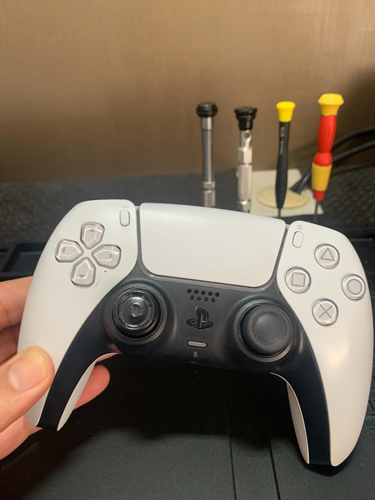 Controle PlayStation na bancada da Control Prime, com ferramentas de precisão ao fundo